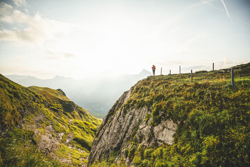 Via Alpina, 9. Etappe, Engstlenalp-Meiringen: Jana steht am Abgrund, blickt gegen die Sonne und das Panorama der Berner Alpen