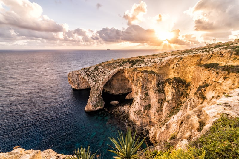 Sunset over the "Blue Grotto". A famous arch rock formation on the island country of Malta. Located in the Mediterranean Sea, Europe.