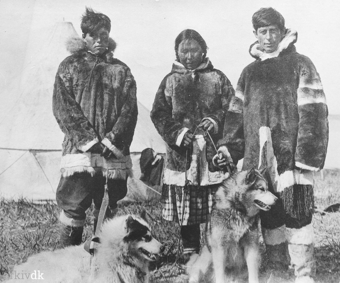 Qâvigarssuaq Miteq Ijaja Kristiansen, Arnarulunnguaq Peary & Knud Rasmussen in front of a tent and standing with two dogs