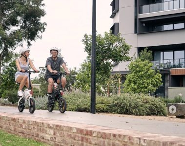 Two people riding DYU D3F E-Bikes through the city