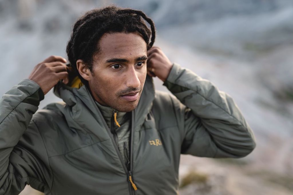 Male hiker wearing a Rab synthetic insulated jacket in the mountains.