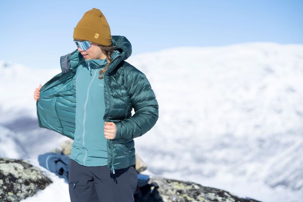 - Female ski tourer in snowy mountains wearing a blue Rab down jacket. 